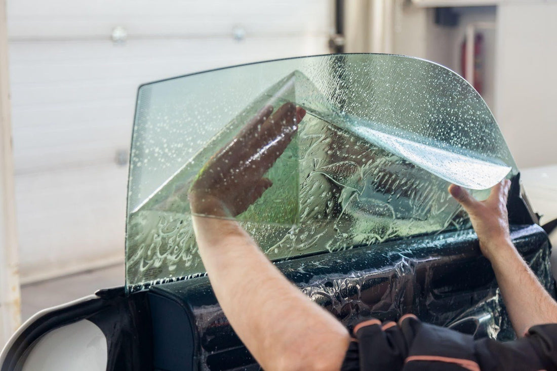 A man diligently cleans the windshield of a car, ensuring clear visibility for safe driving