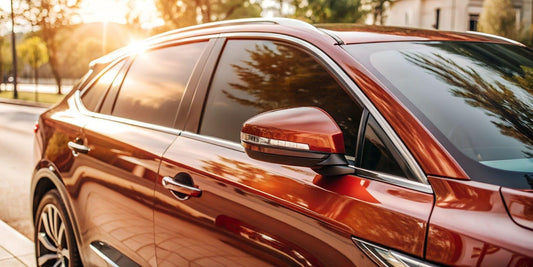 A red SUV parked on the street, with the sun shining brightly overhead