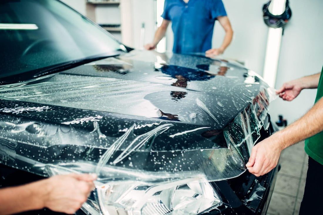 Two men are wrapping a car, focusing on its design and protection
