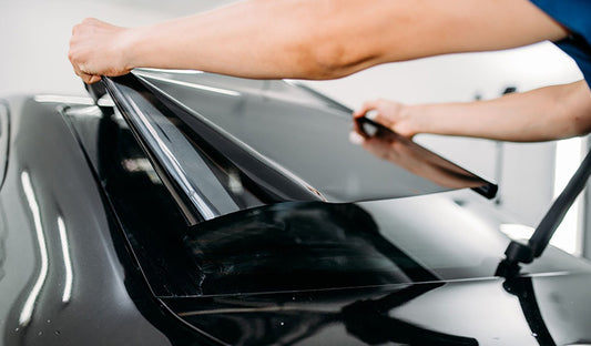 A man applying nano ceramic tint to a black car window, featuring ceramic car tinting for superior heat rejection and UV protection