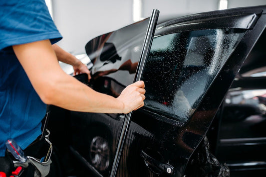 A man is focused on repairing a car door using tools to fix the mechanism