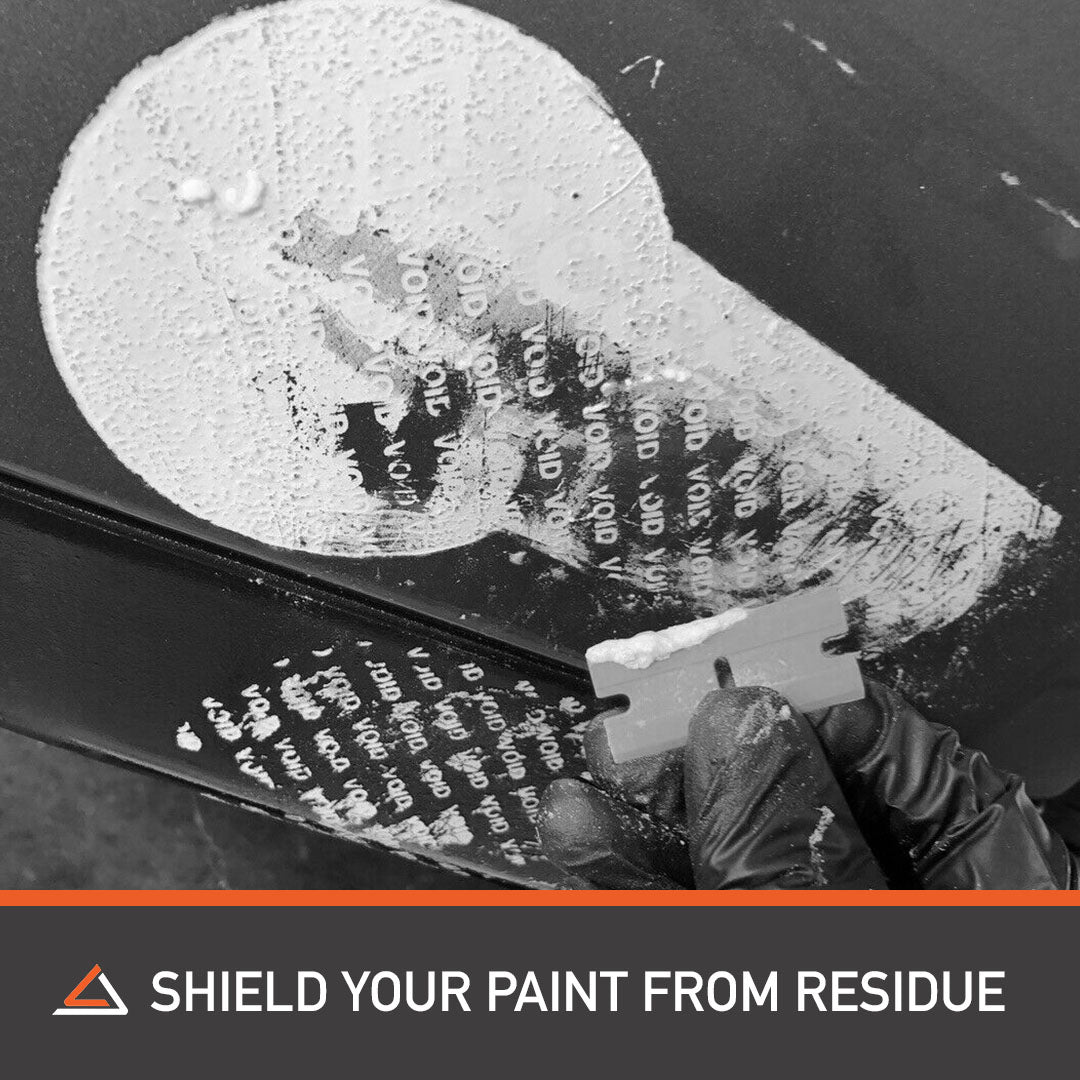 Person carefully scraping paint off car with scraper, protecting paint from residue.