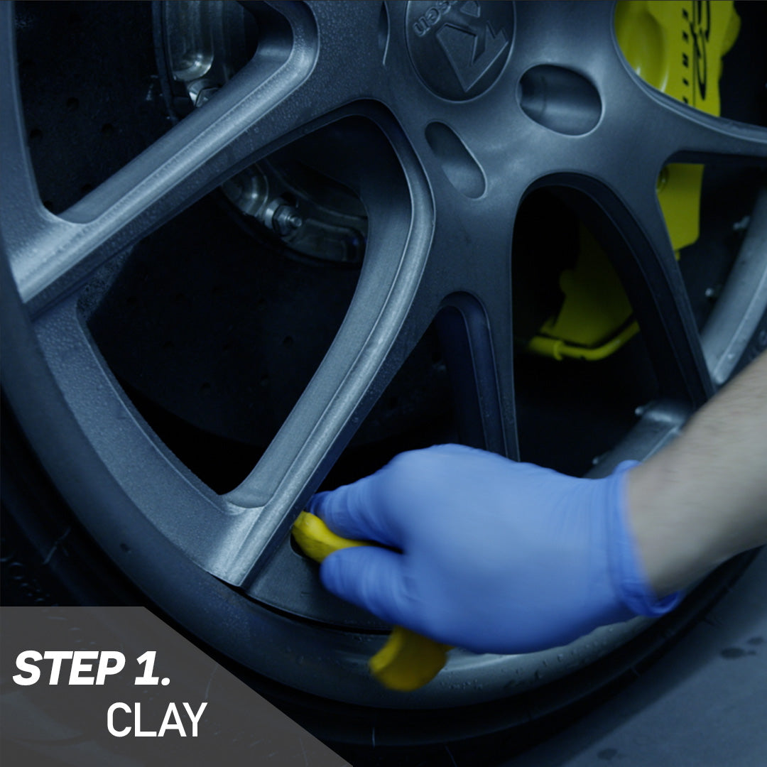 A person wearing blue gloves cleans a tire using a yellow tool, demonstrating proper maintenance techniques.